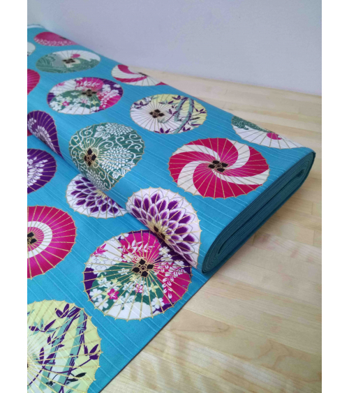 Cotton satin fabric. Paper umbrellas over turquoise-blue background.