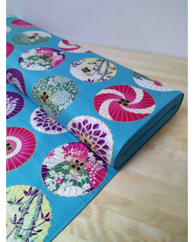 Cotton satin fabric. Paper umbrellas over turquoise-blue background.
