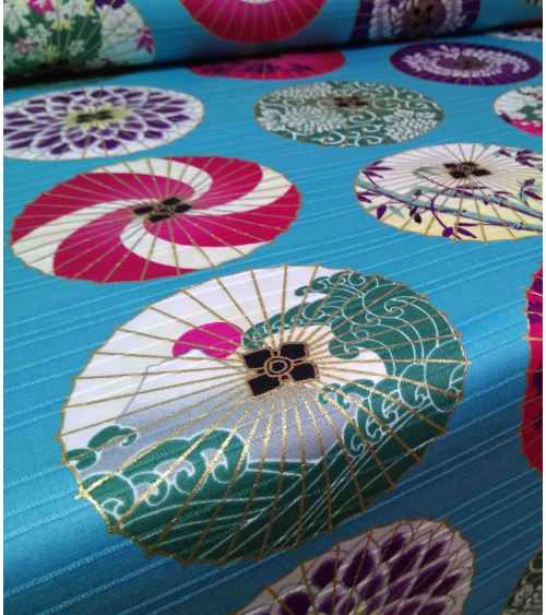 Cotton satin fabric. Paper umbrellas over turquoise-blue background.