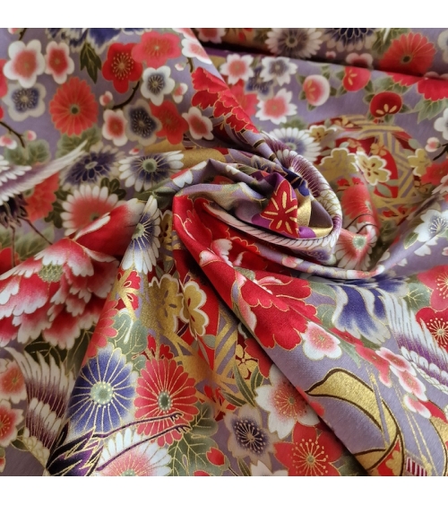Japanese fabric. Multicolored cranes (tsuru) and flowers (hana) over lilac background, outlined in gold.
